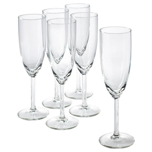 Set of six clear glass champagne flutes on a white background